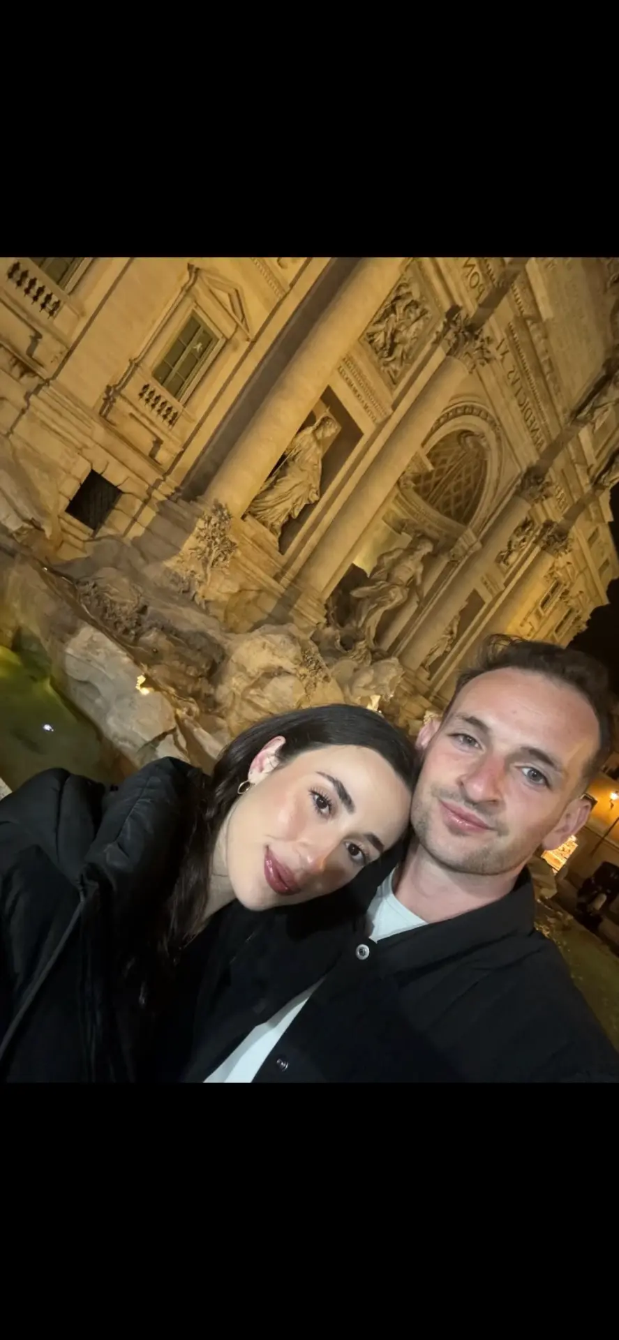 Sam and his girlfriend in front of the illuminated Trevi Fountain in Rome at night