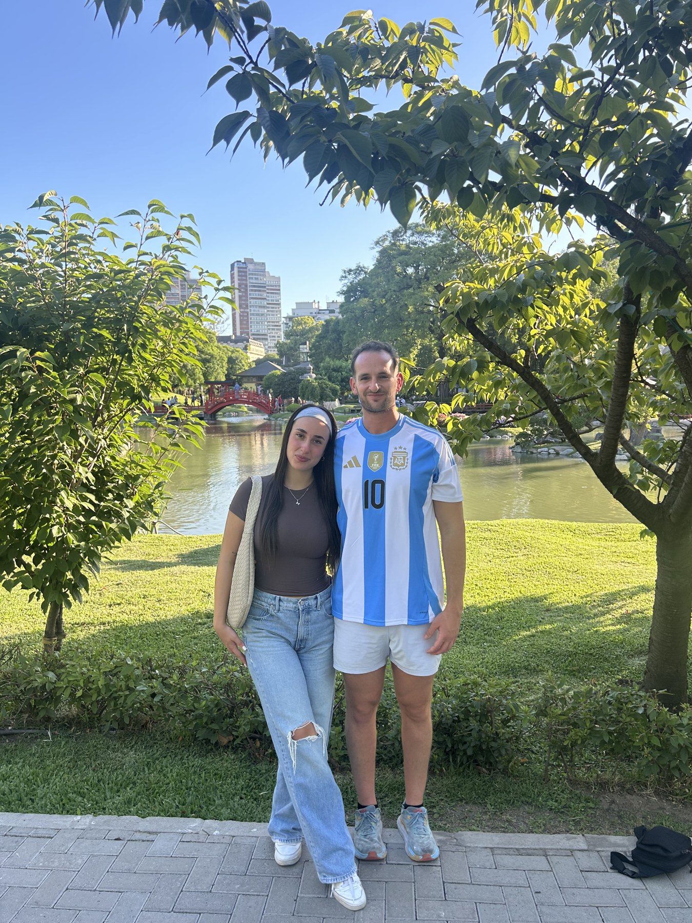 A couple in a park with a pond and red arched footbridge in Buenos Aires, Argentina